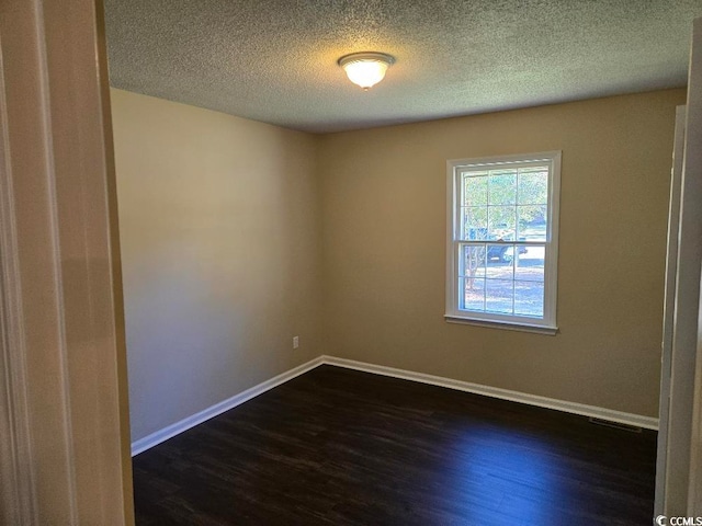 unfurnished room with a textured ceiling and dark hardwood / wood-style floors