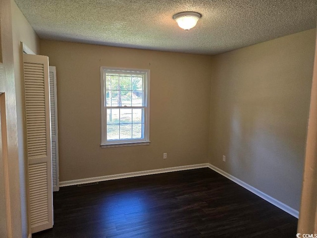 spare room with dark hardwood / wood-style floors and a textured ceiling