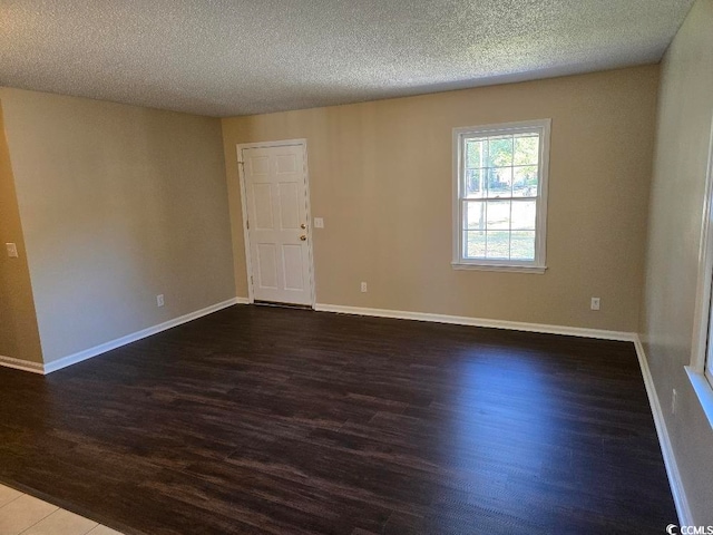 unfurnished room with dark wood-type flooring and a textured ceiling