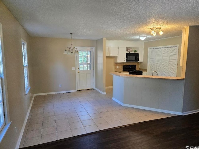 kitchen featuring white cabinetry, black appliances, a textured ceiling, decorative light fixtures, and light wood-type flooring