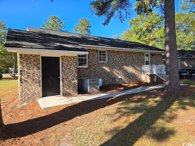 rear view of house with central air condition unit and a yard