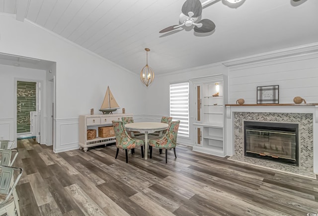 dining space with vaulted ceiling with beams, dark hardwood / wood-style floors, ceiling fan, ornamental molding, and a tiled fireplace