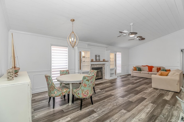 dining room featuring plenty of natural light, crown molding, a fireplace, and dark wood-type flooring