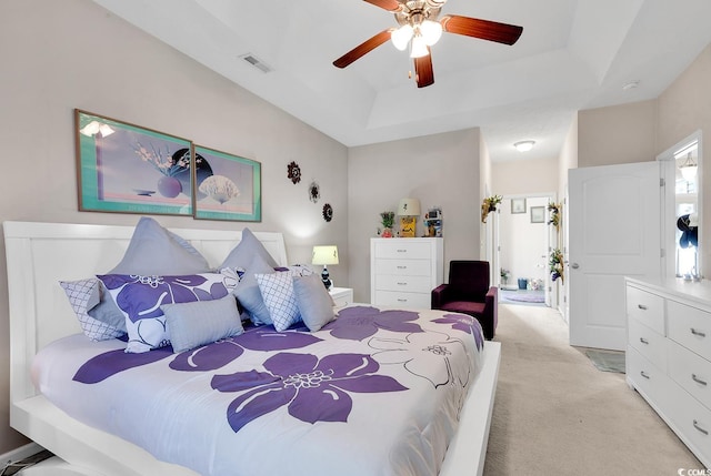 bedroom featuring light carpet, a raised ceiling, and ceiling fan