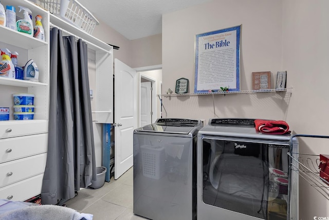 laundry area featuring washing machine and dryer, a textured ceiling, and light tile patterned flooring