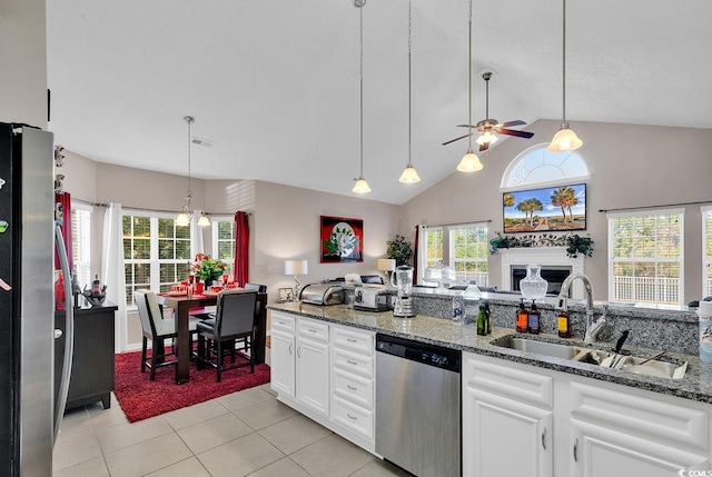 kitchen with light tile patterned floors, appliances with stainless steel finishes, white cabinetry, dark stone counters, and pendant lighting