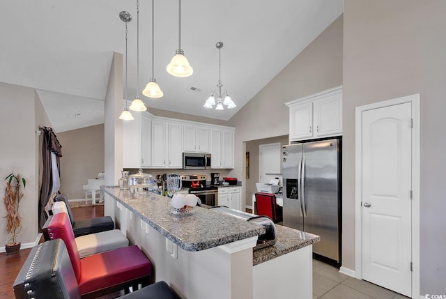 kitchen featuring white cabinetry, appliances with stainless steel finishes, kitchen peninsula, and a kitchen breakfast bar