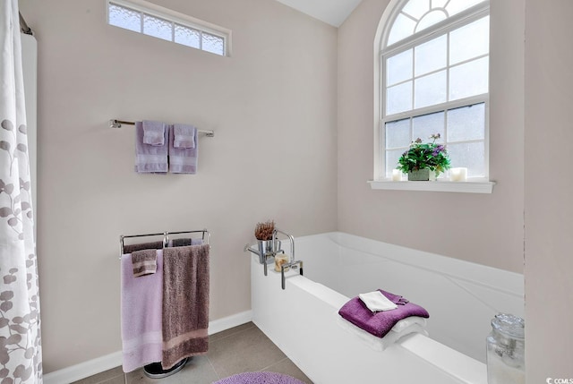 bathroom with a bathtub, a healthy amount of sunlight, and tile patterned floors