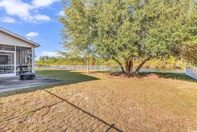 view of yard featuring a water view, a sunroom, and a patio