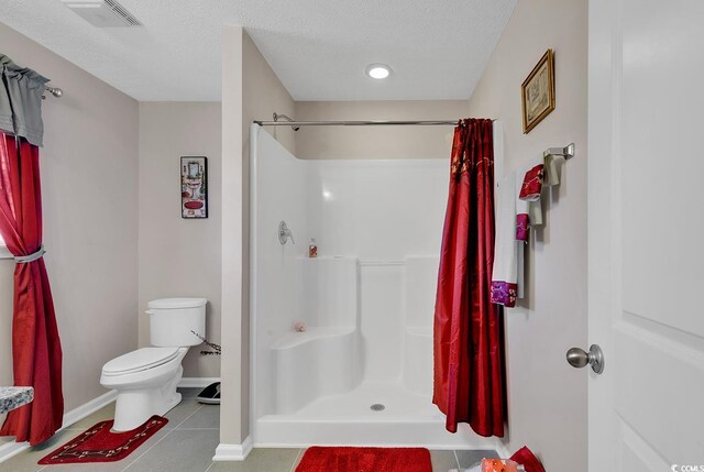 bathroom with toilet, tile patterned floors, walk in shower, and a textured ceiling