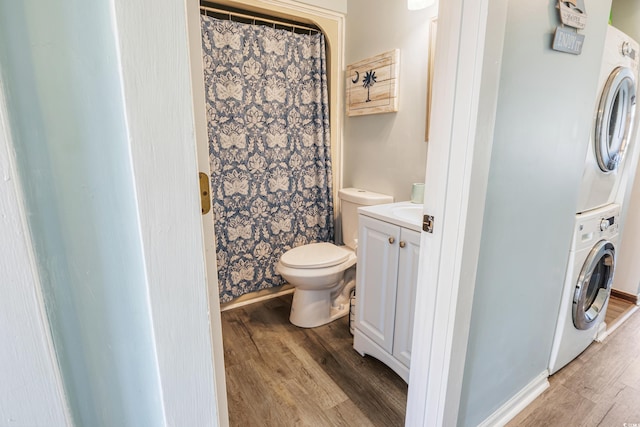 bathroom with stacked washing maching and dryer, hardwood / wood-style floors, vanity, a shower with curtain, and toilet