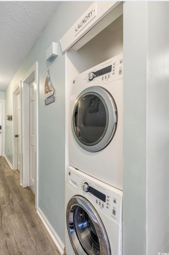 laundry room with stacked washer / dryer, dark hardwood / wood-style floors, and a textured ceiling