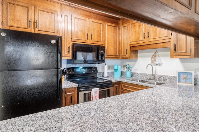 kitchen featuring light stone countertops, sink, and black appliances