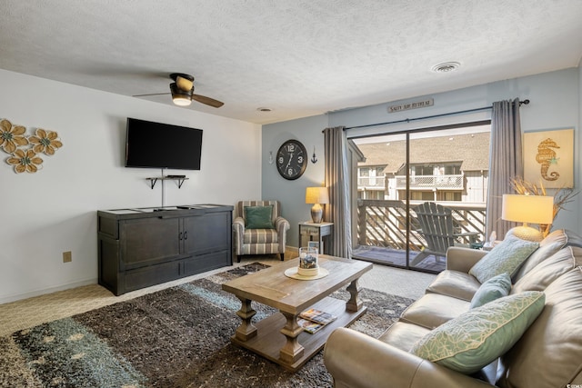 living room with ceiling fan, carpet flooring, and a textured ceiling