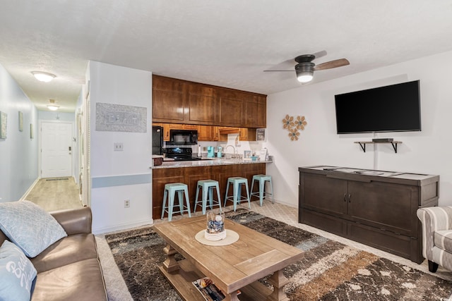 living room featuring ceiling fan, sink, and a textured ceiling