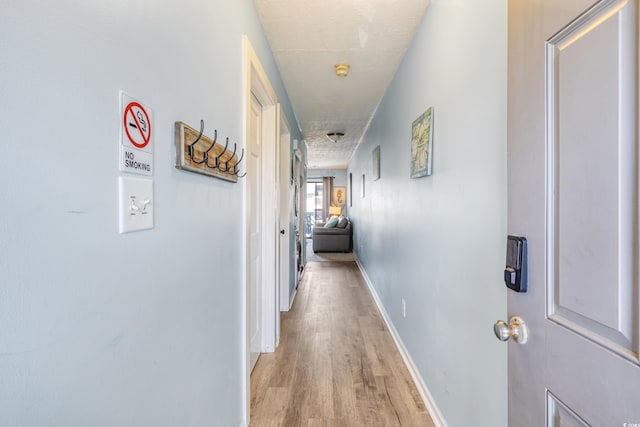 hallway with light hardwood / wood-style floors and a textured ceiling