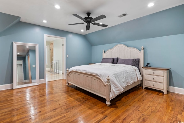 bedroom with ceiling fan, vaulted ceiling, ensuite bathroom, and hardwood / wood-style floors