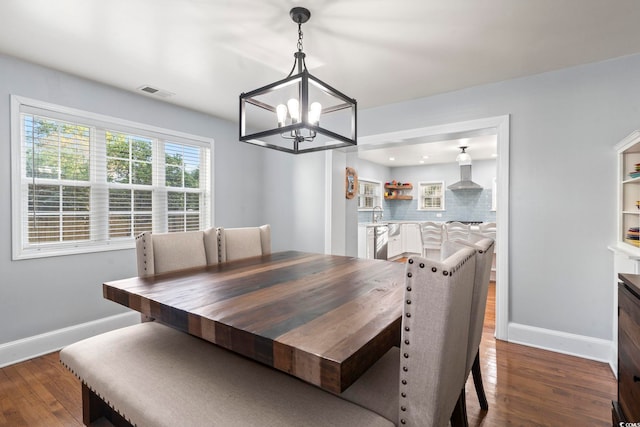 dining area featuring sink, dark wood-type flooring, and an inviting chandelier