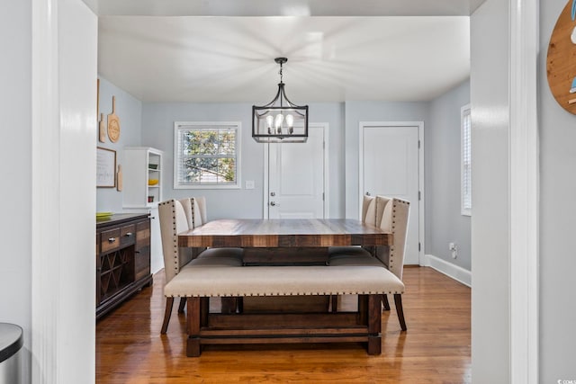 dining area with wood-type flooring and an inviting chandelier