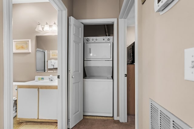 laundry room featuring stacked washer / dryer, sink, and dark carpet