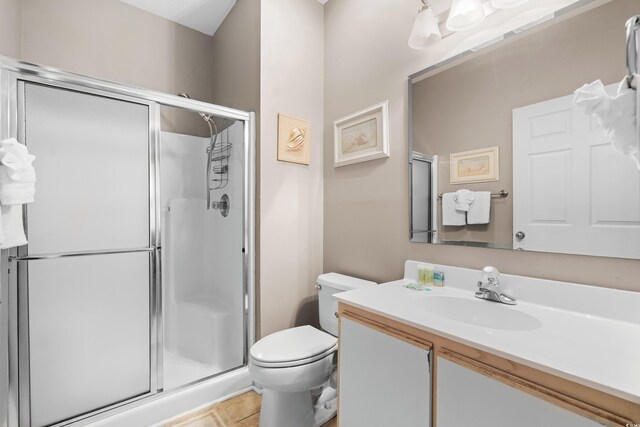 bathroom featuring vanity, a shower with shower door, toilet, and tile patterned flooring