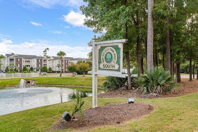 community sign featuring a water view and a yard