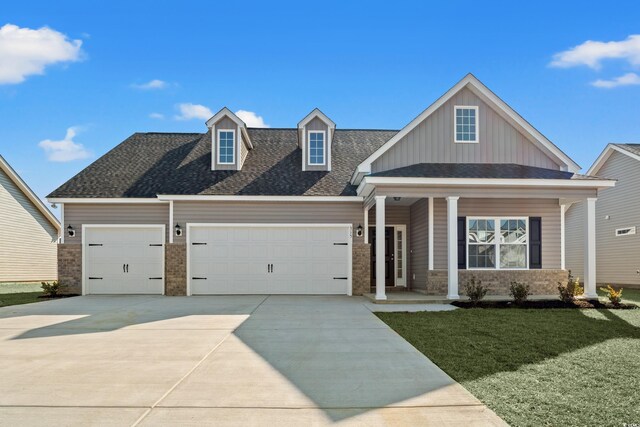 view of front of property with covered porch, a lawn, and a garage