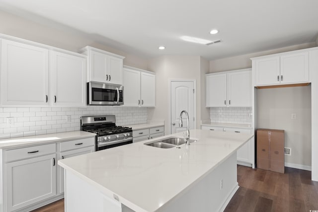 kitchen with appliances with stainless steel finishes, an island with sink, white cabinetry, and sink