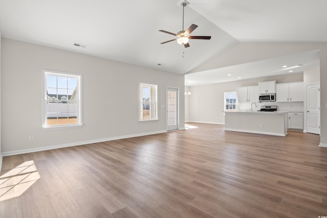 unfurnished living room featuring ceiling fan, lofted ceiling, light hardwood / wood-style flooring, and sink