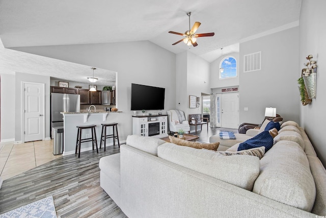 living room with high vaulted ceiling, light wood-type flooring, and ceiling fan