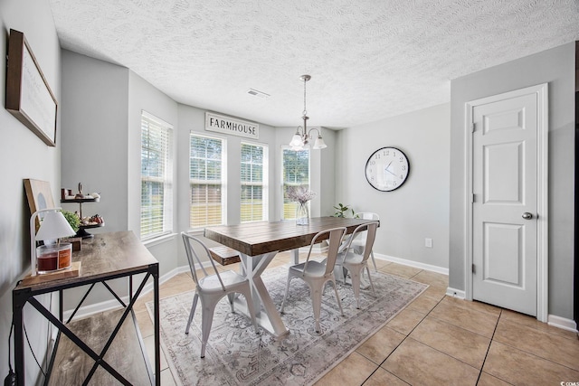 tiled dining area featuring a notable chandelier and a textured ceiling