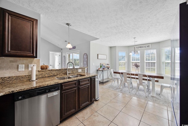 kitchen featuring light stone countertops, sink, lofted ceiling, stainless steel dishwasher, and light tile patterned floors