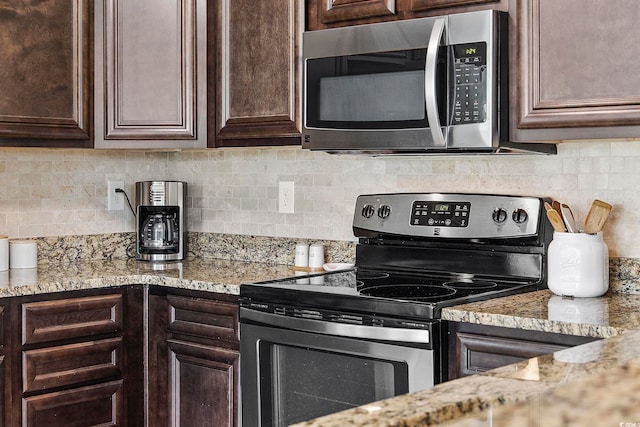 kitchen featuring appliances with stainless steel finishes, decorative backsplash, light stone countertops, and dark brown cabinets