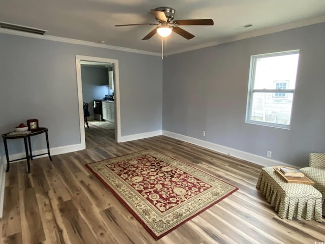 sitting room featuring hardwood / wood-style flooring, crown molding, and ceiling fan