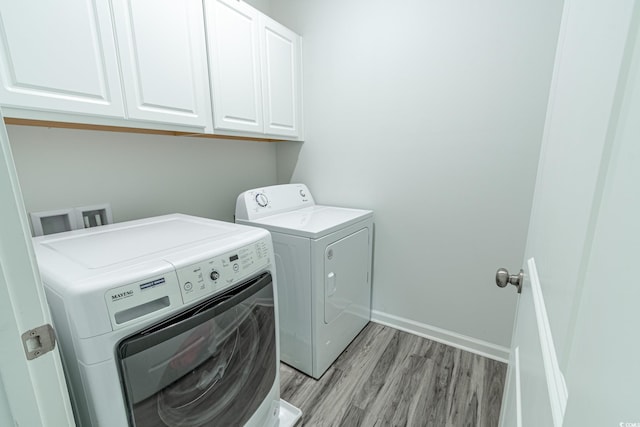 washroom with light wood-type flooring, cabinet space, baseboards, and washer and dryer