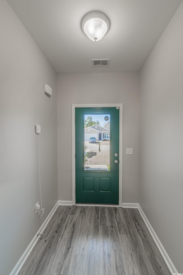 doorway to outside featuring baseboards, visible vents, and wood finished floors