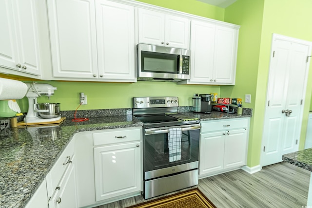 kitchen with white cabinetry, light hardwood / wood-style flooring, stainless steel appliances, and dark stone counters