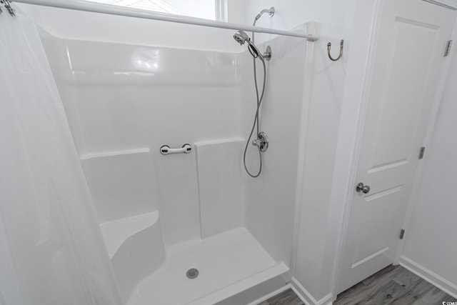 full bath with a shower stall and wood finished floors