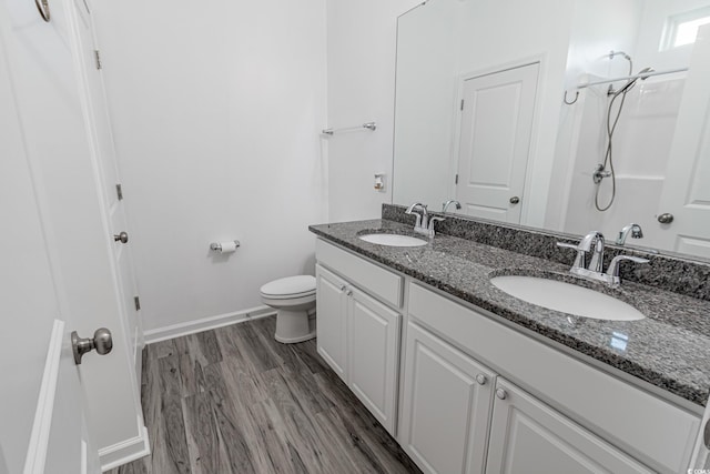 full bath featuring double vanity, a sink, baseboards, and wood finished floors