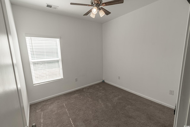 empty room with ceiling fan, dark colored carpet, visible vents, and baseboards