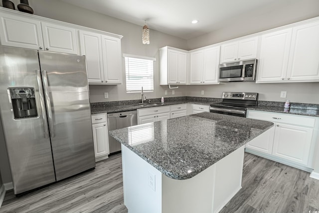 kitchen featuring stainless steel appliances, a center island, white cabinets, and a sink