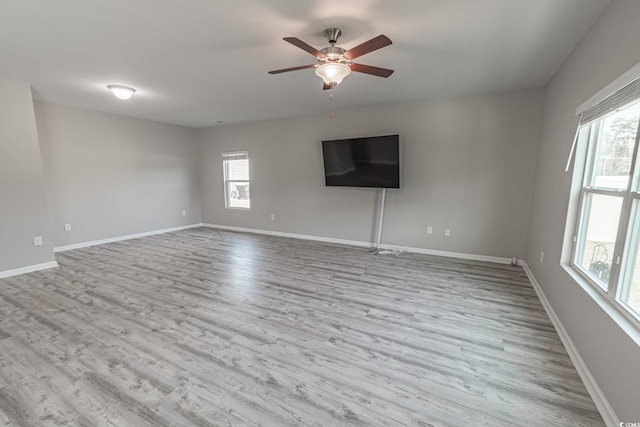 unfurnished living room featuring a healthy amount of sunlight, light wood-style flooring, and baseboards