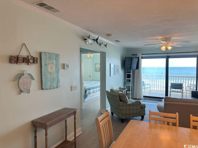 dining room featuring a textured ceiling, hardwood / wood-style floors, ceiling fan, and crown molding