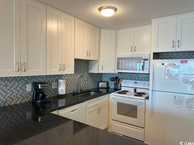 kitchen with decorative backsplash, sink, white cabinetry, white appliances, and dark stone countertops