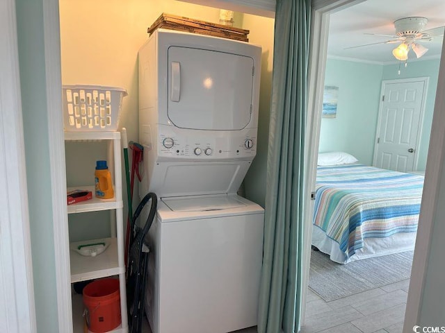 laundry room with stacked washer and dryer, ceiling fan, and crown molding