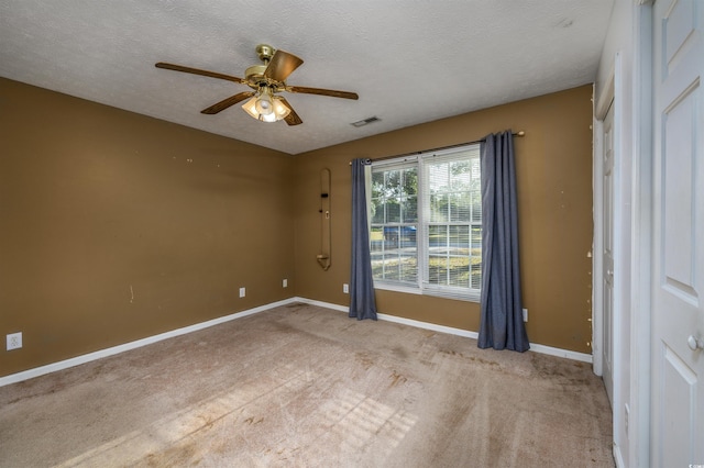 carpeted empty room featuring ceiling fan and a textured ceiling