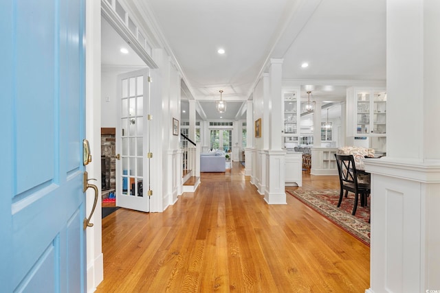 entrance foyer featuring decorative columns, light hardwood / wood-style floors, and ornamental molding