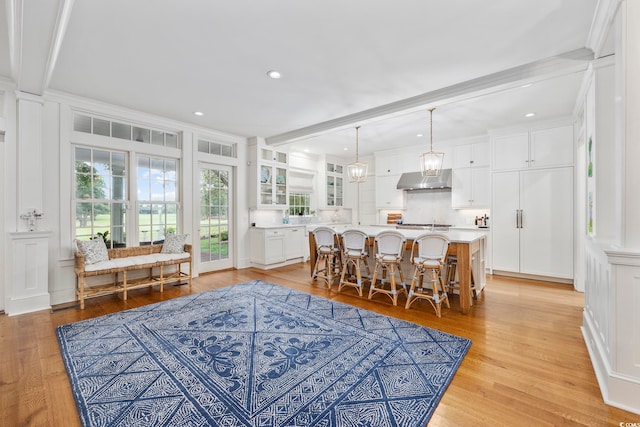 dining room with light wood-type flooring, ornamental molding, and beam ceiling