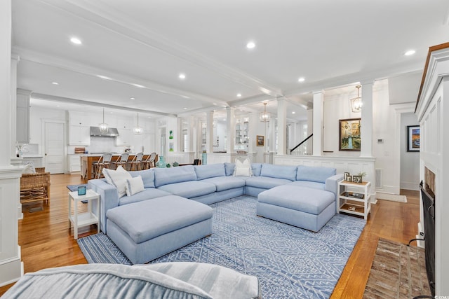 living room with ornate columns, light hardwood / wood-style floors, and ornamental molding