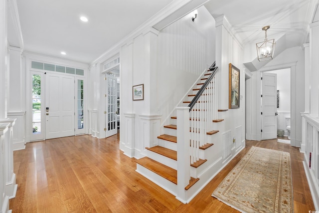 entrance foyer featuring light wood-type flooring, a notable chandelier, and crown molding